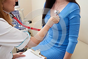 Doctor listening stethoscope with to heart of young female patient