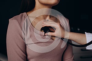 Doctor listening stethoscope with to heart of young female patient.