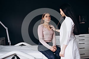 Doctor listening stethoscope with to heart of young female patient.