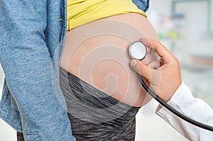 Doctor is listening to heartbeat baby of pregnant woman