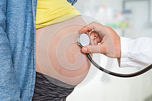 Doctor is listening to heartbeat baby of pregnant woman