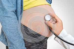 Doctor is listening to heartbeat baby of pregnant woman