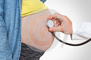 Doctor is listening to heartbeat baby of pregnant woman