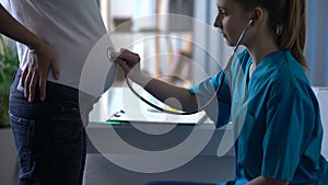 Doctor listening to heartbeat of child in abdomen of future mother, pregnancy