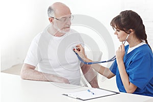 Doctor listening to senior man heartbeat