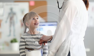 The doctor listens to the child with a stethoscope