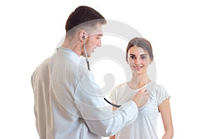 The doctor listens to the heart with a stethoscope from a young girl isolated on a white background