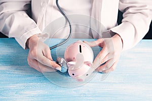 The doctor listens to the piggy bank with a stethoscope