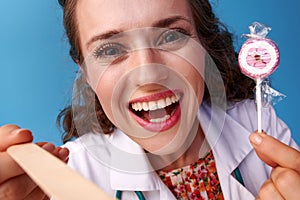 Doctor with lollipop using a spatula to examine throat