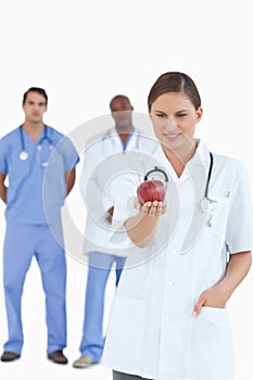 Doctor looking at apple with colleagues behind her