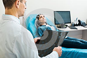 Doctor looking through CT results while conducting electroencephalography photo