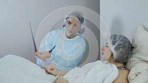 Doctor looking at and discussing the results of computed tomography of a patient lying on a bed in an emergency room