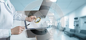 Doctor looking through a magnifying glass at documents