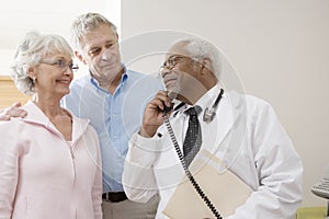 Doctor Looking At Patients While Using Landline Phone photo