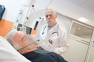 Doctor looking at senior male patient inhaling through oxygen mask