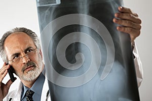 Doctor Looking at X-Ray and Using Cell Phone