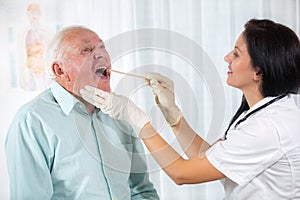 Doctor looks in the throat an older man