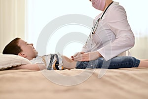 The doctor looks at the tummy of a laughing baby.