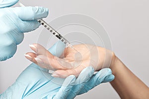 The doctor makes injections of botulinum toxin on the palms of a woman against hyperhidrosis. Women`s cosmetology, skin care