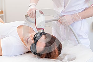 The doctor makes laser hair removal on the face of a woman in the salon. An alternative way to permanently remove