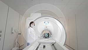 Doctor makes an MRI scan for a patient in a clinic. The girl lies in the MRI device. Magnetic resonance imaging in the