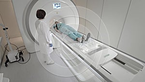 Doctor makes an MRI scan for a patient in a clinic. The girl lies in the MRI device. Magnetic resonance imaging in the