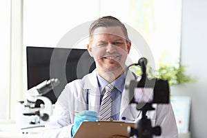 Doctor makes notes in folder in front video camera