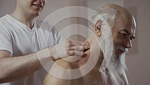 Doctor makes a therapeutic massage of shoulders to senior man