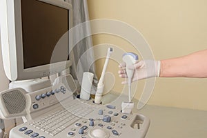 The doctor makes an ultrasound in the hospital.The hand of an elderly in a white glove holds a tool for scanning the internal
