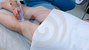 Doctor makes ultrasound of knee joint for man using ultrasound scanner, closeup.