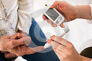 Doctor making diabetes blood test on senior woman, closeup