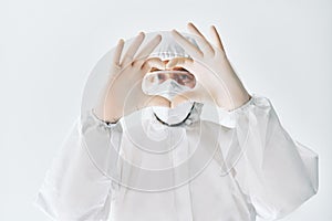 Doctor making heart shape symbol with hands wearing protective medical suit