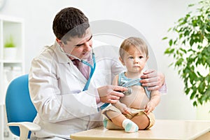 Doctor man examining heartbeat of kid boy with