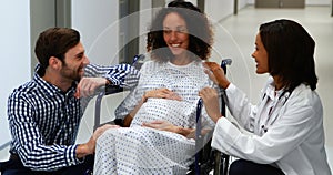 Doctor and man interacting with pregnant woman in corridor