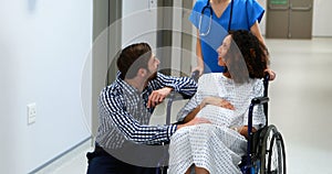 Doctor and man interacting with pregnant woman in corridor