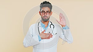 Doctor man raising hand to take oath, promising to be honest and to tell truth keeping hand on chest