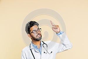 Doctor man showing thumbs up and pointing on blank space place for advertisement promotion logo