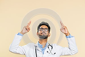 Doctor man showing thumbs up and pointing on blank space place for advertisement promotion logo