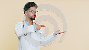 Doctor man showing thumbs up and pointing on blank space place for advertisement promotion logo