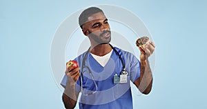 Doctor, man and studio for donut, apple and choice with thinking for healthcare by blue background. Medic, person or