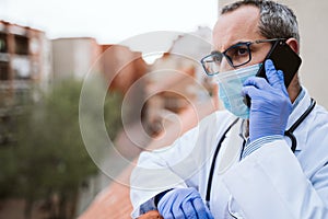 Doctor man taking a break, using mobile phone. Wearing protective gloves, mask and stethoscope. coronavirus covid-19 concept