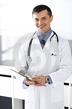 Doctor man using clipboard for filling up medication history records. Perfect medical service in clinic. Physician at