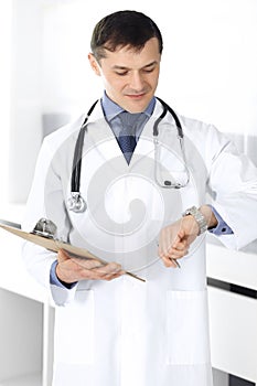 Doctor man using clipboard for filling up medication history records. Perfect medical service in clinic. Physician at