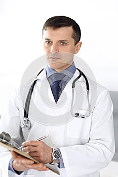 Doctor man using clipboard for filling up medication history records. Perfect medical service in clinic. Physician at