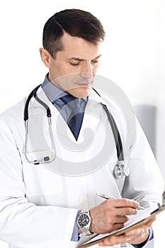 Doctor man using clipboard for filling up medication history records. Perfect medical service in clinic. Physician at