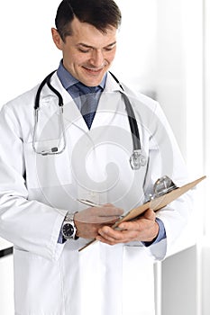 Doctor man using clipboard for filling up medication history records. Perfect medical service in clinic. Physician at