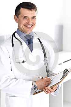 Doctor man using clipboard for filling up medication history records. Perfect medical service in clinic. Physician at