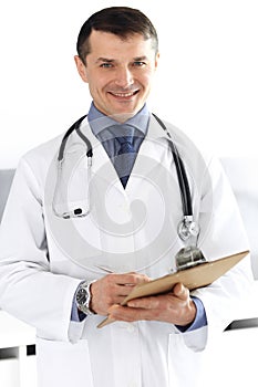 Doctor man using clipboard for filling up medication history records. Perfect medical service in clinic. Physician at
