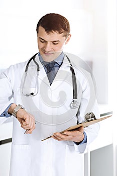 Doctor man using clipboard for filling up medication history records. Perfect medical service in clinic. Physician at