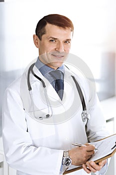 Doctor man using clipboard for filling up medication history records. Perfect medical service in clinic. Physician at